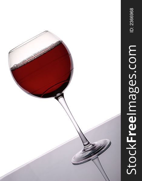 Glass of red wine shot against a white background with back lighting. Glass of red wine shot against a white background with back lighting.