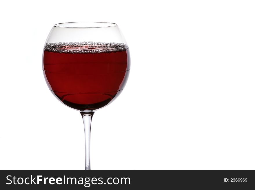 Red wine against a white background in a subtly striped wine glass. Red wine against a white background in a subtly striped wine glass.