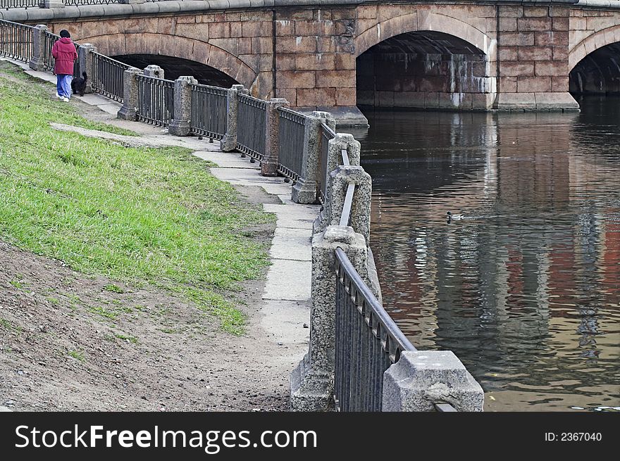 Woman walking her dog along river embankment