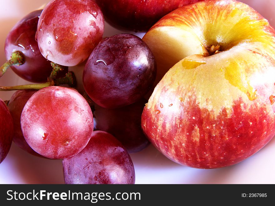 Fresh red grapes and cut apple with water drops on the plate. Fresh red grapes and cut apple with water drops on the plate