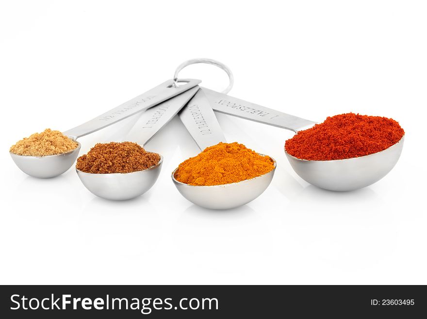 Spice selection of ground ginger, mace, turmeric and cayenne pepper in measuring spoons over white background. Spice selection of ground ginger, mace, turmeric and cayenne pepper in measuring spoons over white background.