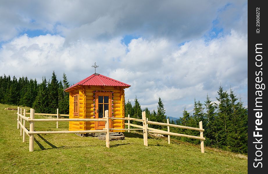 A small wood church is situated on the pasture surrounded with coniferous forest. A small wood church is situated on the pasture surrounded with coniferous forest.