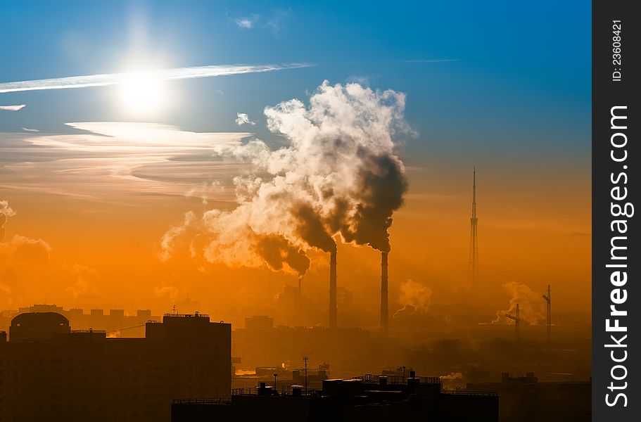 Sswirling smoke from the chimneys, buildings, and radio tower at sunrise