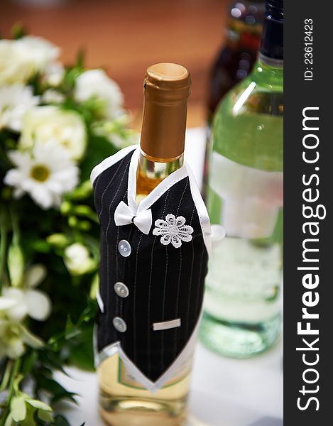 Bottle of vine in the costumes of groom on wedding table