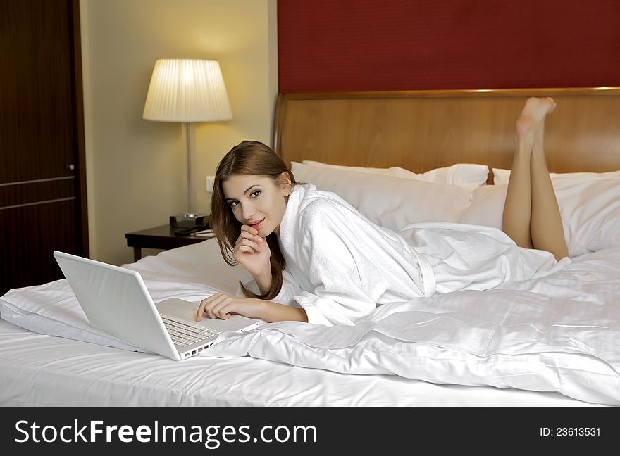 Young Woman Lying On A White Sofa With A Laptop.