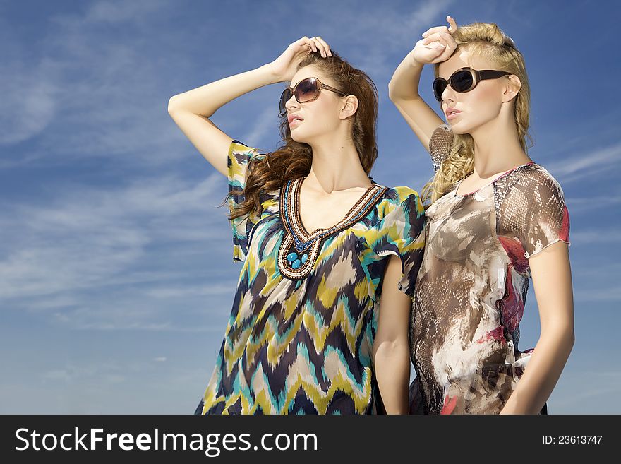 Two Beautiful Girl In Sunglasses On Blue Sky