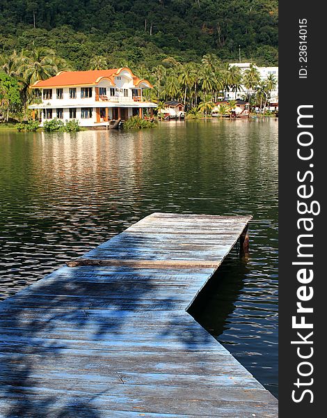 Pier on lake in background with villa and tropical landscape