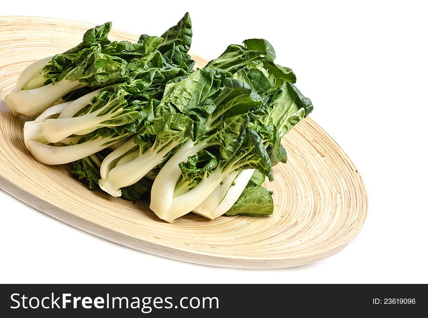 Bunch of baby Bok Choy on a bamboo platter isolated on white. Bunch of baby Bok Choy on a bamboo platter isolated on white.