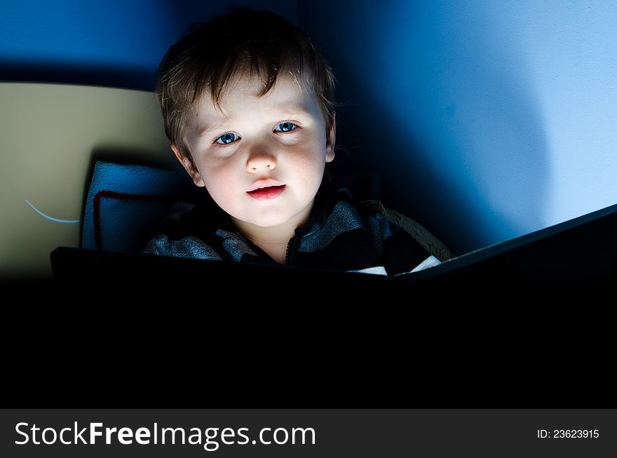 Little boy reading a book in his bed at night. Little boy reading a book in his bed at night