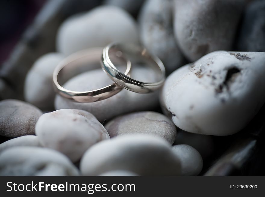 Wedding rings on sea stone background
