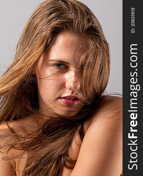 A fun image of a gorgeous young women with wet hair and face, with her hair blowing across her face. A fun image of a gorgeous young women with wet hair and face, with her hair blowing across her face
