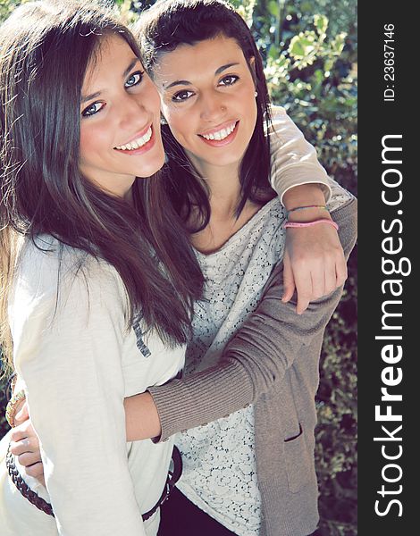 Two young smiling sisters embraced . Outdoor and natural light . Two young smiling sisters embraced . Outdoor and natural light .