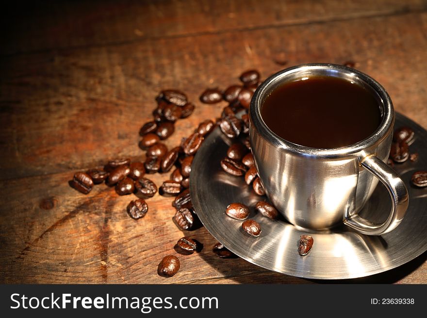 Steel coffee cup and beans on wooden surface. Steel coffee cup and beans on wooden surface