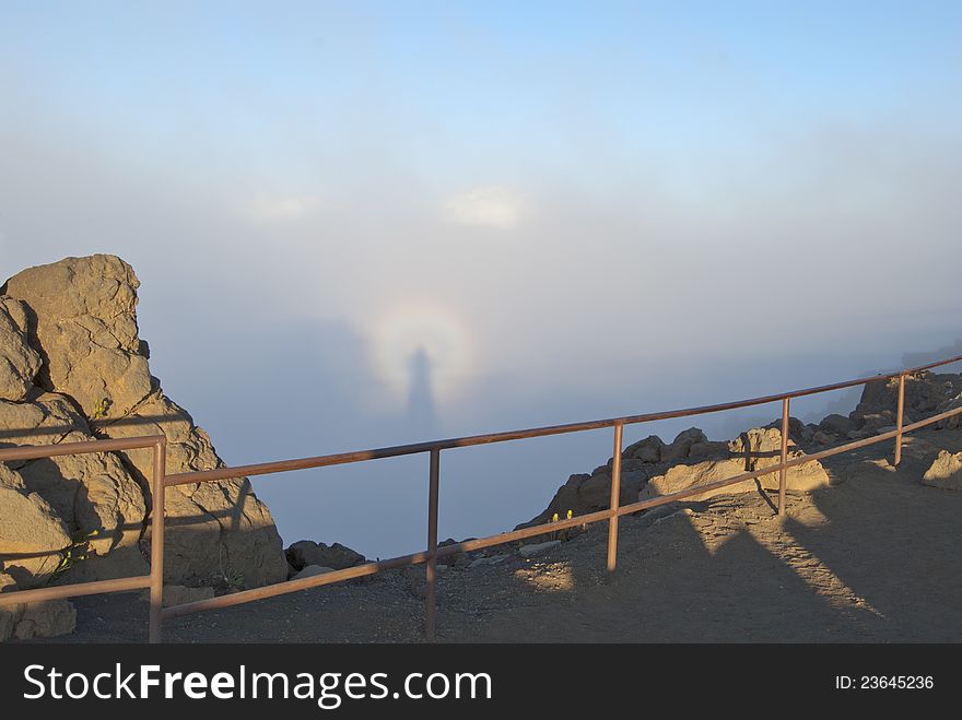 A unique natural phenomenon. The shadow of the photographer in the clouds. The setting sun behind the photographer. Haleakala volcano, the island of Maui, Hawaii