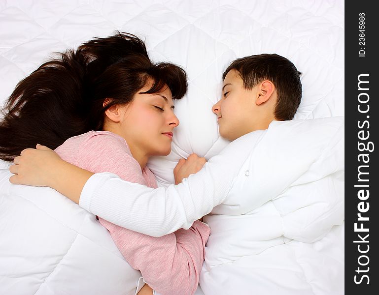 Mother and son sleeping covered with white blanket. Son hugging hes mother. Mother and son sleeping covered with white blanket. Son hugging hes mother