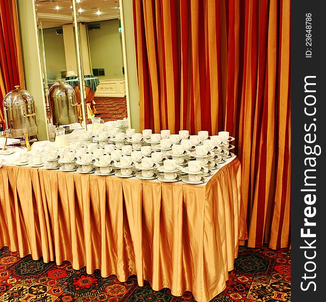 Boiler and  tea cups on the table in the hall of the conference center. Boiler and  tea cups on the table in the hall of the conference center