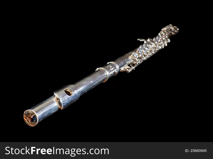 Standard silver flute oblique view with selective focus on mouthpiece, isolated on black. Standard silver flute oblique view with selective focus on mouthpiece, isolated on black