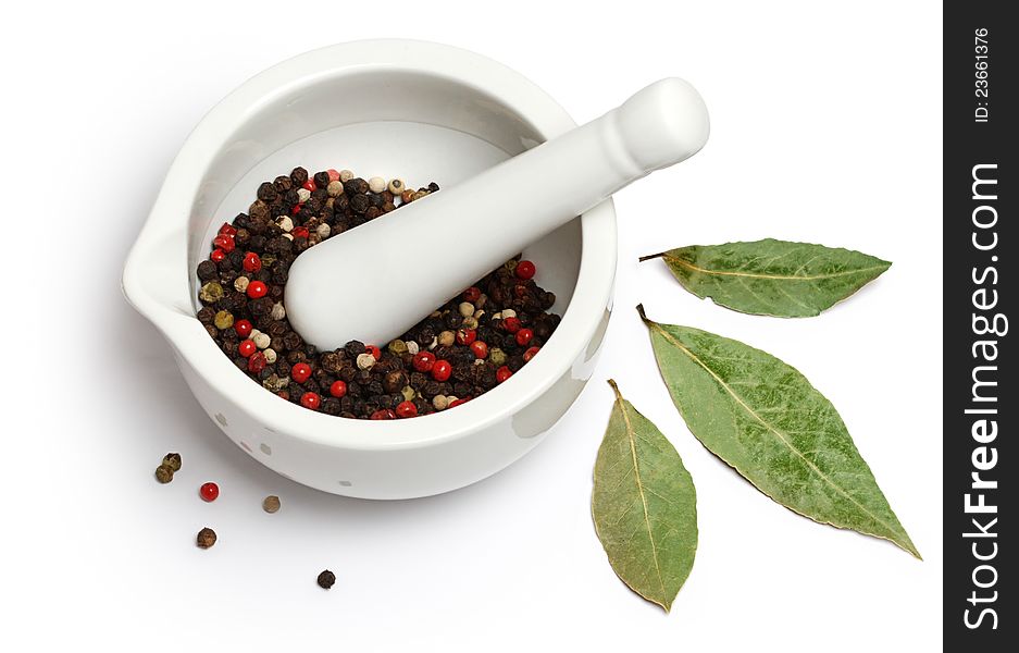 Porcelain mortar and pestle with spices (pepper and bay leaves)