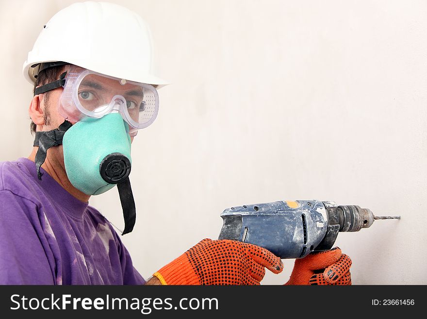 Worker in a hardhat holding electric drill. Worker in a hardhat holding electric drill