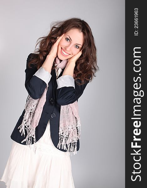 Beautiful smiling girl in a blue coat over gray background. Studio shot.