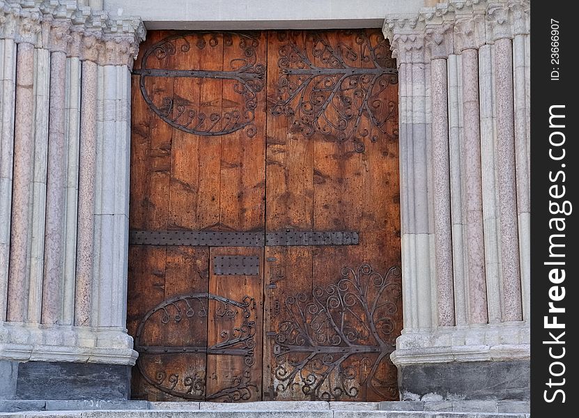 Large wooden door and fitting of a cathedral flanked by marble columns. Large wooden door and fitting of a cathedral flanked by marble columns