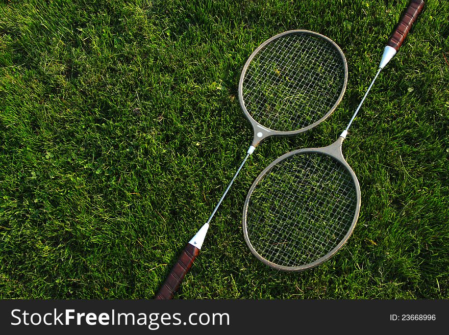 Badminton rackets resting upon green grass. Badminton rackets resting upon green grass