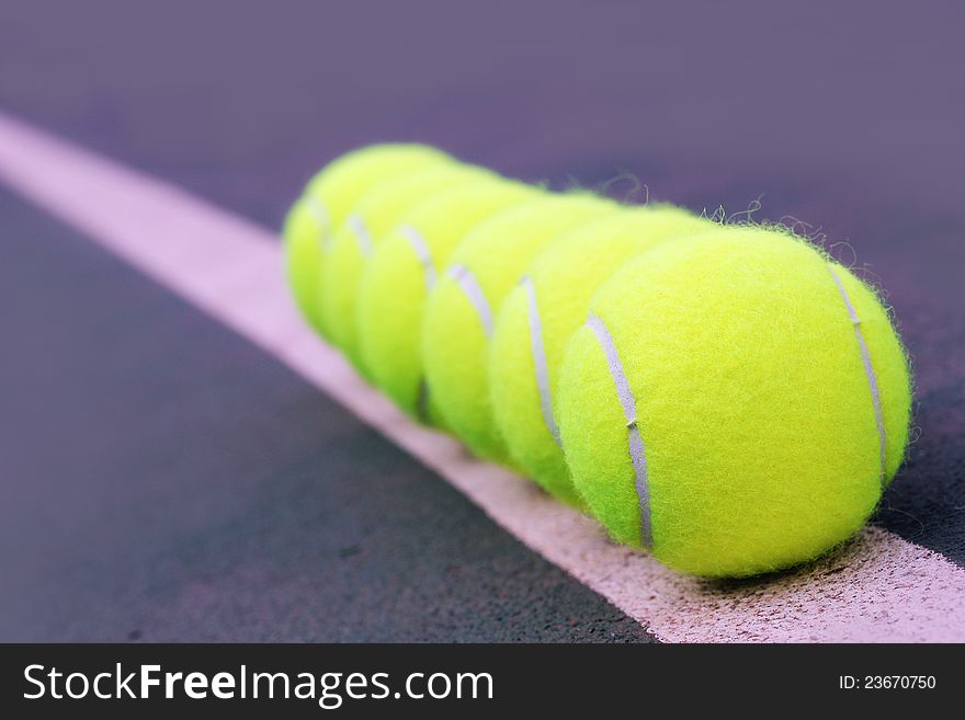 Tennis balls close up arranged in row on hard court synthetic tennis turf. Tennis balls close up arranged in row on hard court synthetic tennis turf