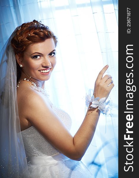 Happy bride near window in wedding day