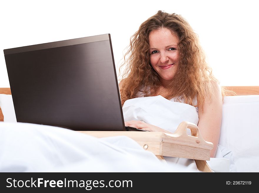 Woman with laptop in bed home office