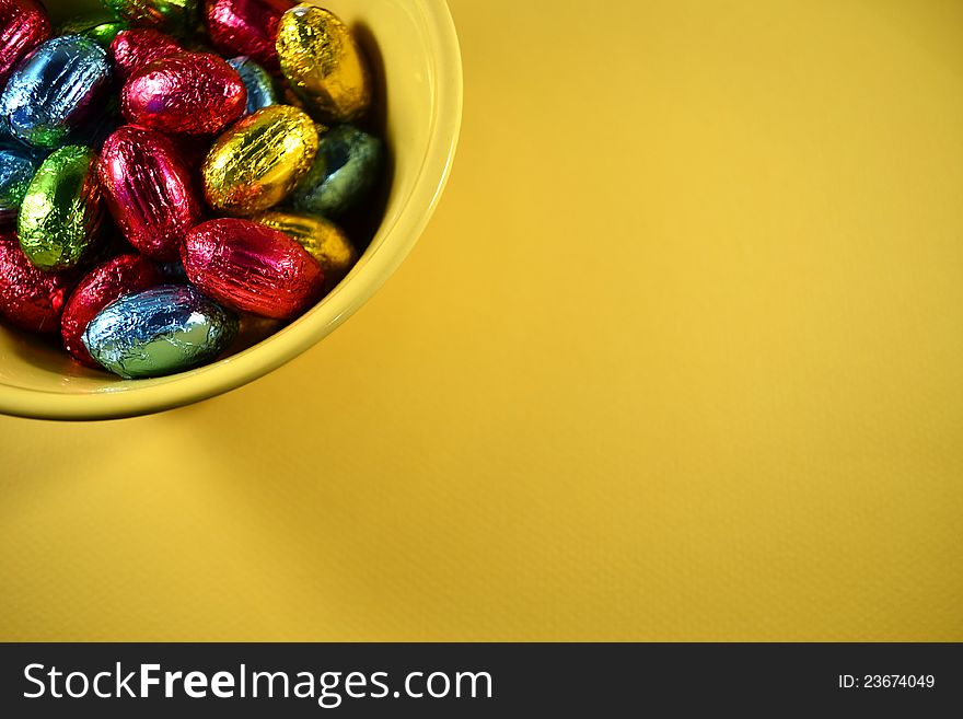 Easter candy in a yellow bowl with yellow background. Easter candy in a yellow bowl with yellow background