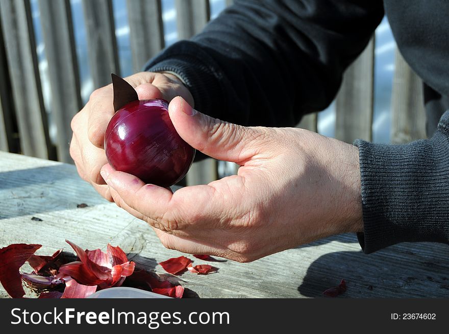 Man's hands peeling a red onion with a knife. Man's hands peeling a red onion with a knife