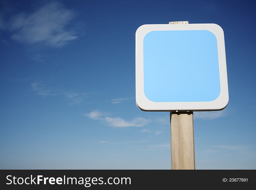 Foreground of a square white  sign with blue sky. Foreground of a square white  sign with blue sky