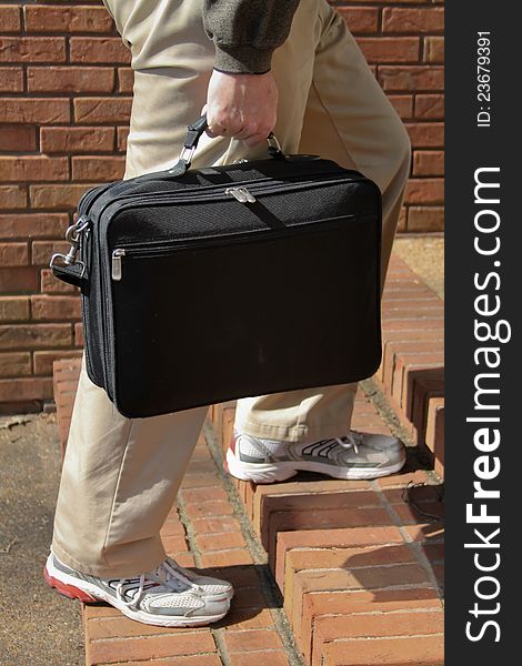 Business man with briefcase in tennis shoes suggests Casual Friday