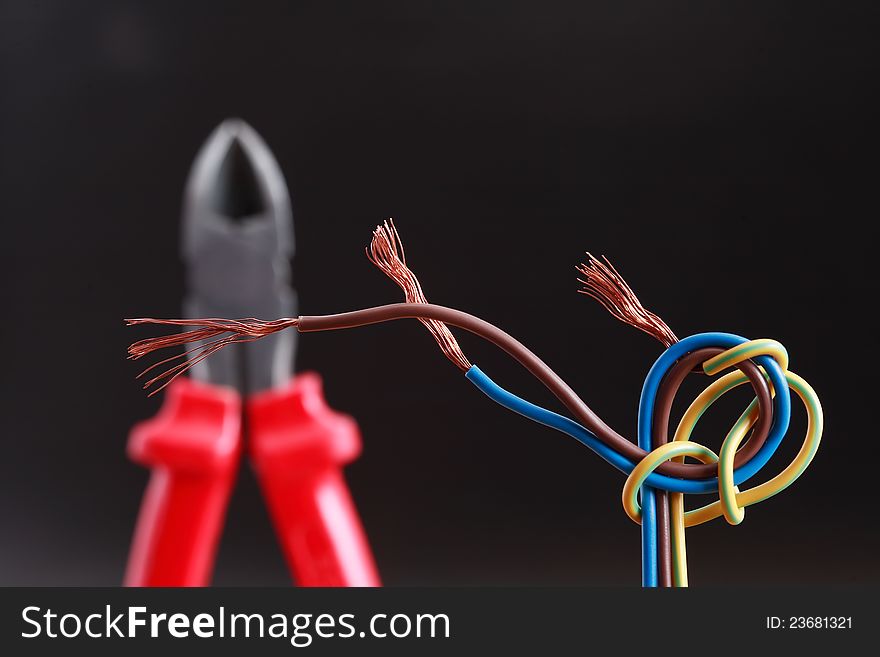 Knotted bundle of colored cable on dark background with wire-cutter. Knotted bundle of colored cable on dark background with wire-cutter