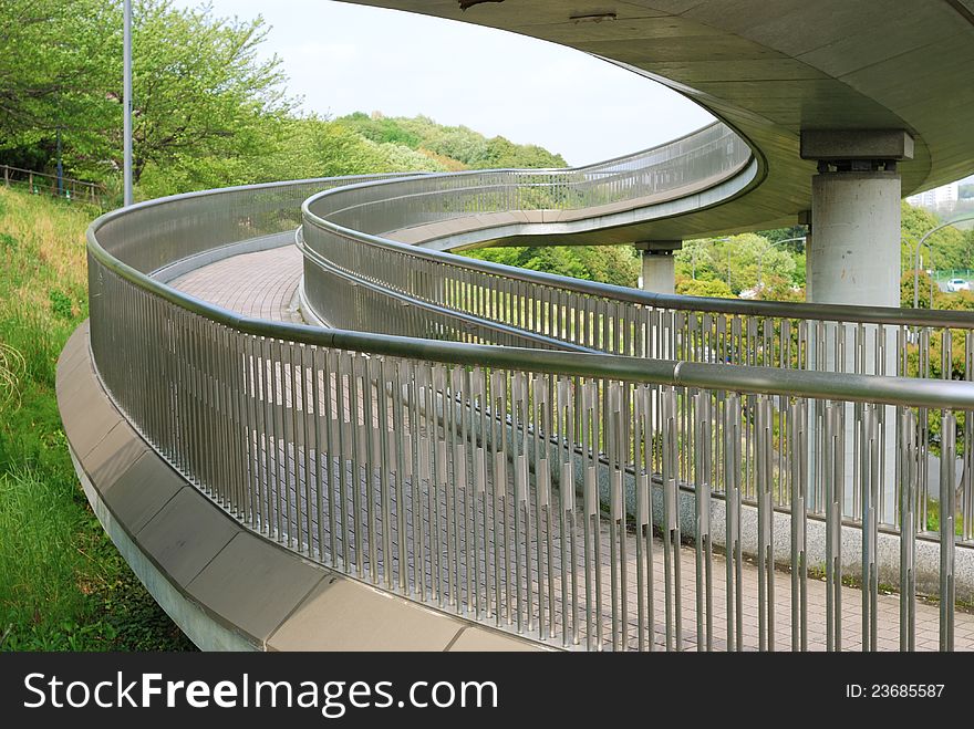 Outdoor bent pathway with tiled floor and metallic handrails