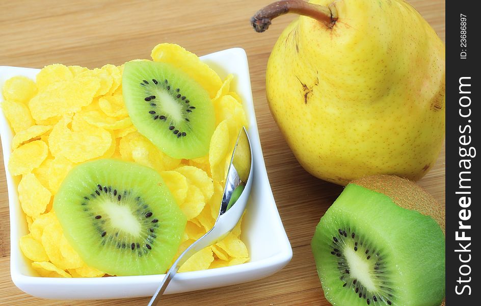 A concept of healthy and light meal; corn flakes, pear and kiwi on the table. A concept of healthy and light meal; corn flakes, pear and kiwi on the table.