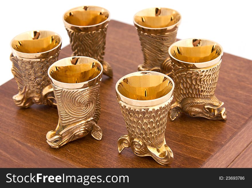 Glasses for spirits - six golden glasses in a shape of wild animals on a wooden box. Glasses for spirits - six golden glasses in a shape of wild animals on a wooden box