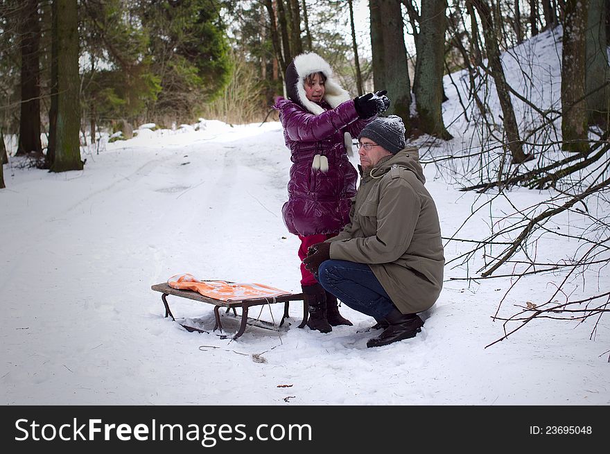 Daughter playing with father in winter, throwing snow