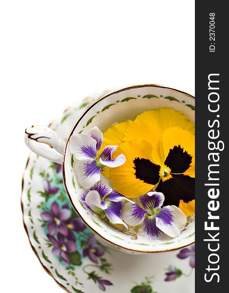 Teacup with pansies and violets on white background - shallow depth of field. Teacup with pansies and violets on white background - shallow depth of field.