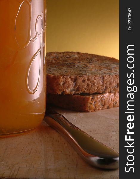 Cosy closeup of toast, marmalade and knife on a wooden board with homestlye cottage feel. Cosy closeup of toast, marmalade and knife on a wooden board with homestlye cottage feel