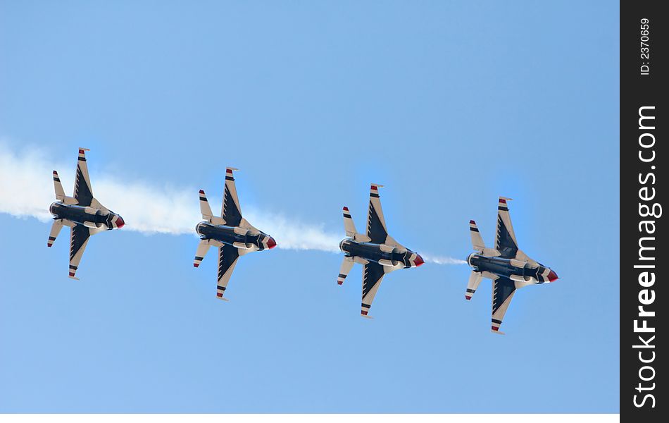 Four fighter jets flying in formation against a clear blue sky