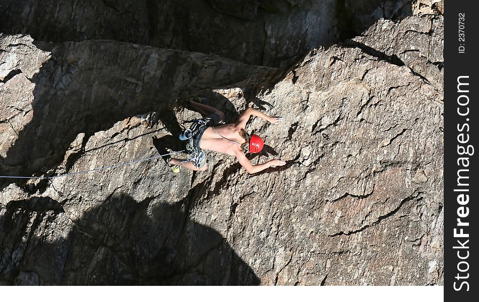 A rock climber works his way up a rock face protected by a rope clipped into bolts. He is wearing a helmet and quickdraws dangle from his harness. The route is in the desert southwest United States. Mt Lemmon, Arizona. A rock climber works his way up a rock face protected by a rope clipped into bolts. He is wearing a helmet and quickdraws dangle from his harness. The route is in the desert southwest United States. Mt Lemmon, Arizona.