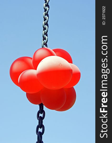 Red balloons on a chain against a blue sky