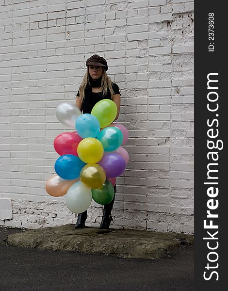 Sad girl with balloons on brick wall background. Sad girl with balloons on brick wall background