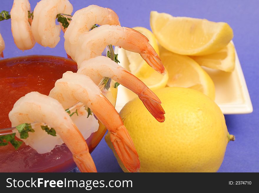 Isolated shrimp cocktail with lemons on blue