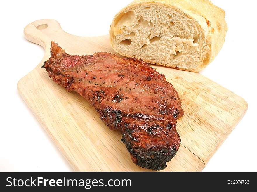 Isolated photo of a steak on a cutting board with bread on white