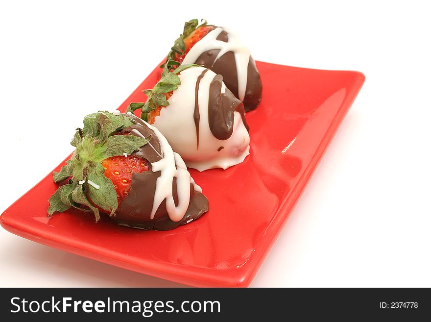 Isolated photo of chocolate covered strawberrys on a red plate on white