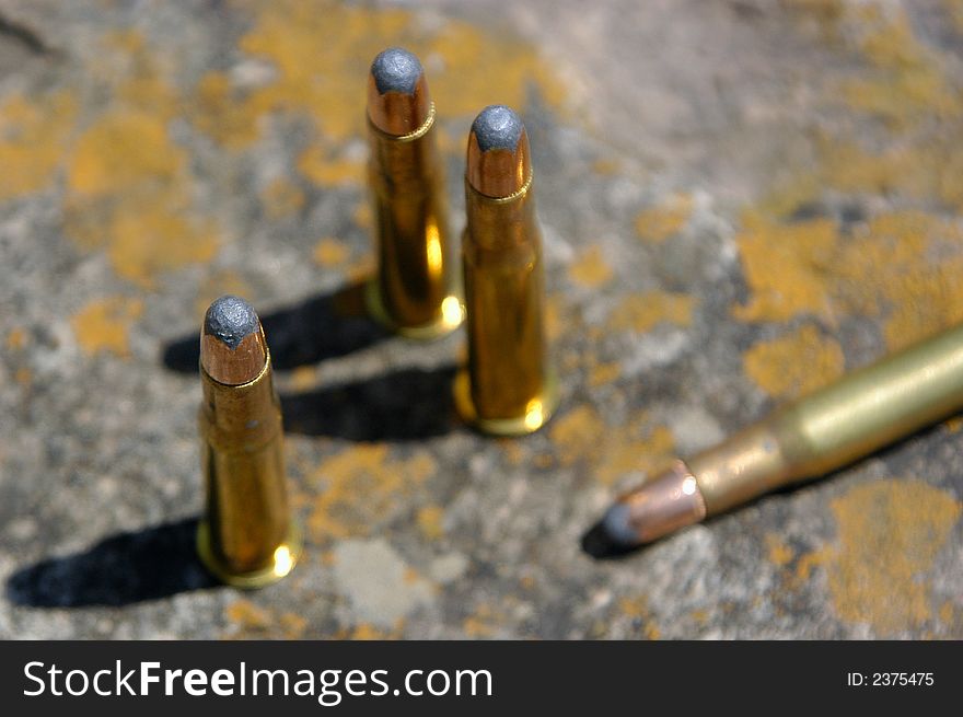 A small group of bullets sitting on a chunk of old sandstone.