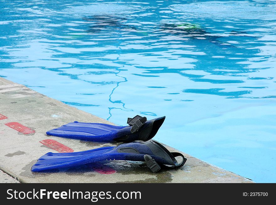 Two blue swim fins by the swimming pool