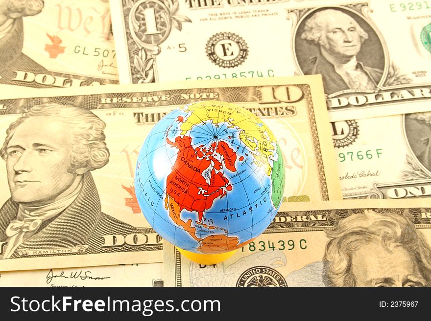 A globe sitting on a background of American dollars suggesting a global currency